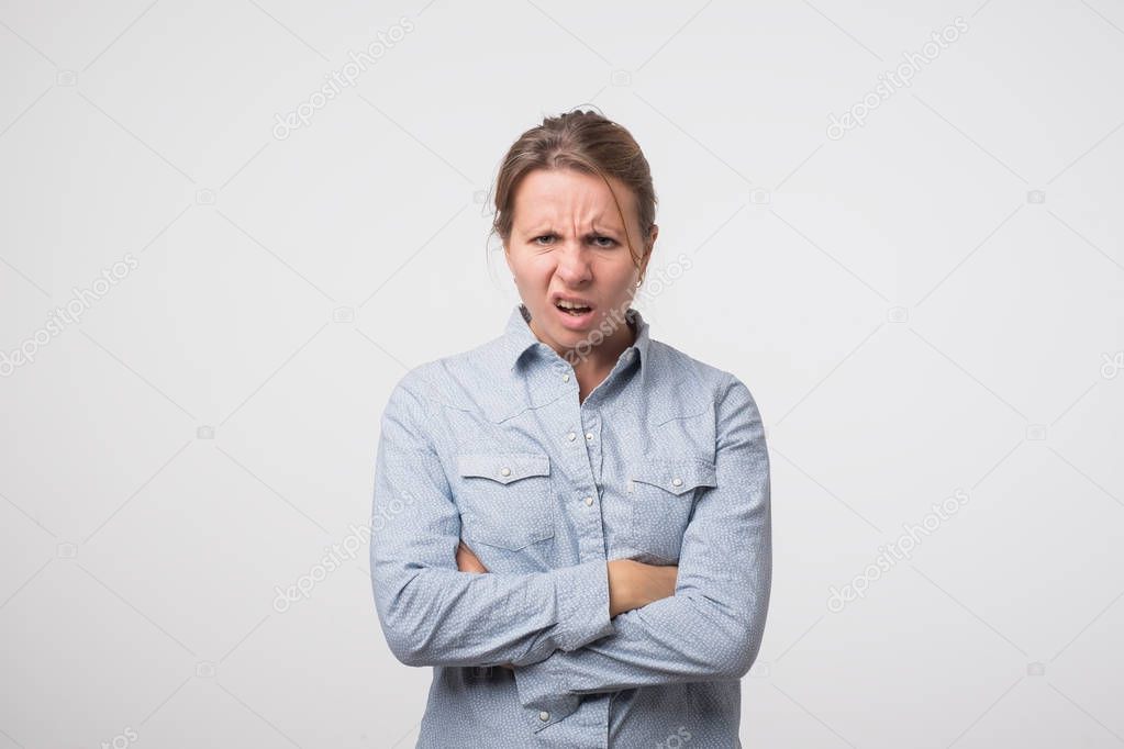 disgusted and frowning young woman on a white background