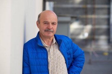 Mavi ceket yaslanmış gri duvar içinde poz yakışıklı orta yaşlı adam. Açık erkek portre. Sokak fotoğraf.