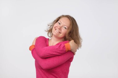 Gülümseyen Avrupa kadın sıcak kazaklı kameraya bakıyor. gri arka plan üzerinde izole. Kendinden emin ve bağımsız olması