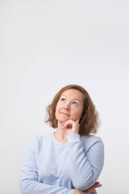 Orta düşünme ve bakılması, hakkında bir fikir karışık Avrupa kadın yaşlı, gri arka plan üzerinde bir çözüm bulmaya çalışıyorum. Dikey yönlendirme