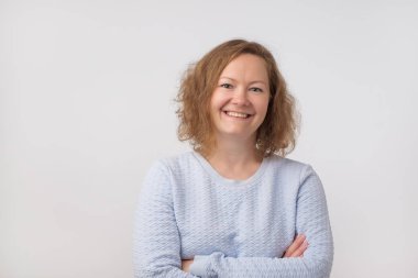 Kameraya bakarak ve gülümseyen, gri arka plan üzerinde izole mavi kazaklı gülümseyen Avrupa Bayan. Kendinden emin ve bağımsız olmak. Yüzündeki nazik ezpression