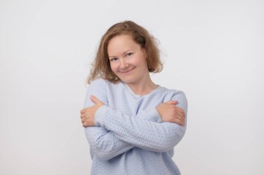 Mavi kazaklı kameraya bakarak Avrupa kadın gülümsüyor, gri arka plan üzerinde izole. Kendinden emin ve bağımsız olmak. Yüzündeki nazik ezpression