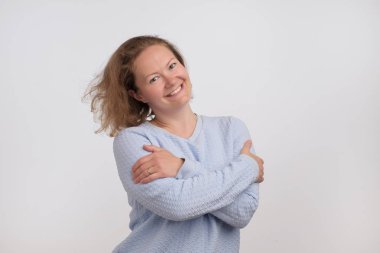 Mavi kazaklı kameraya bakarak Avrupa kadın gülümsüyor, gri arka plan üzerinde izole. Kendinden emin ve bağımsız olmak. Yüzündeki nazik ezpression