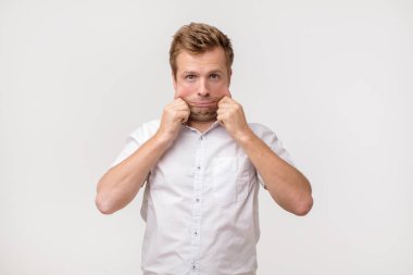 Cilt ve kırışıklıkları sorunları. Beyaz tişörtlü derisi yüz germe yakışıklı beyaz adam. Yüzündeki kilo kaybettikten sonra ilave cilt