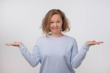 Omuz silkme yapıyor şüpheye mavi kazak giyen Norveçli kadın shrugging. Karışık kız el hareketi işareti bilmiyorum gri arka plan üzerinde