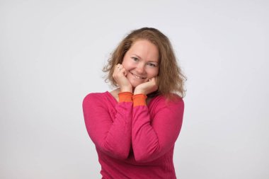 Kameraya bakarak ve gülümseyen, gri arka plan üzerinde izole pembe kazaklı gülümseyen Avrupa Bayan. Kendinden emin ve bağımsız olmak. Yüzündeki nazik ezpression