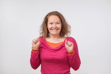 Gülümseyen ve yumrukları suratını yakınındaki tutan sürpriz genç kadın. Satış fiyatları ile şok o. Bu doğru mu.