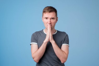 Kendisini affetmesi için mavi t-shirt preslemeler palms birlikte ve kamera, görünümlü yakışıklı genç adam