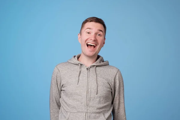 Stijlvolle Europese mens staande lachen over blauwe achtergrond — Stockfoto