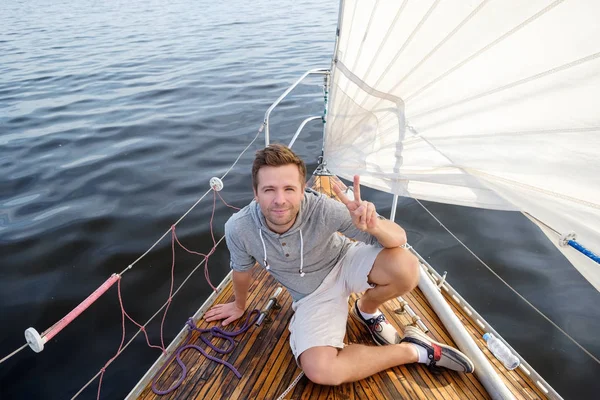 Молодой европейский мужчина, сидящий на яхте и смотрящий на море . — стоковое фото