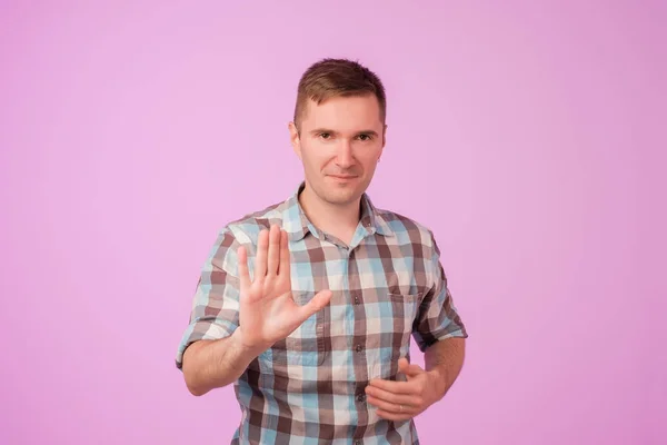 Portrait of european serious young man stretching hand towards camera with stop or hold gesture — Stock Photo, Image