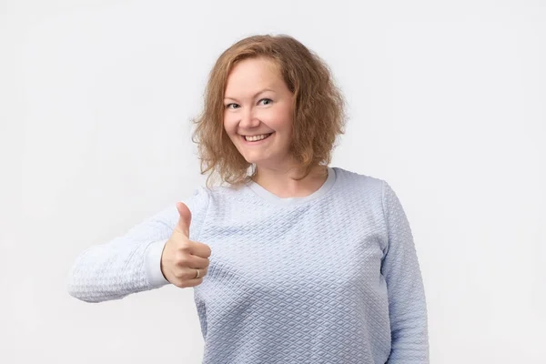 Вывеска "Большой палец". Счастливая европейская женщина в голубой рубашке изолированы на сером фоне . — стоковое фото
