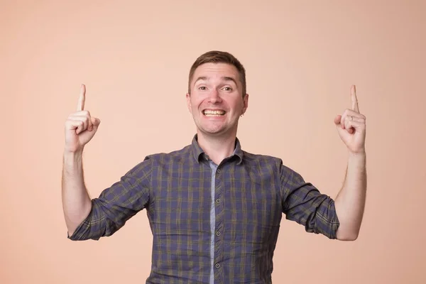 Surpris jeune homme pointant vers le haut avec deux mains. Hé chercher concept — Photo