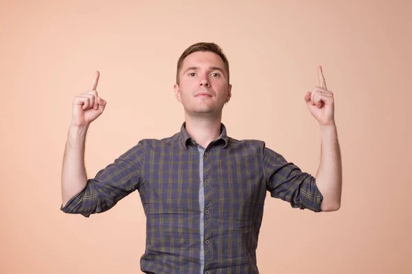 Sorprendido joven apuntando hacia arriba con dos manos. Oye, busca el concepto — Foto de Stock