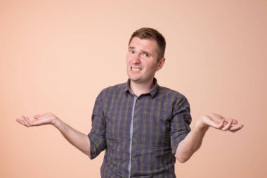 Stüdyo hiçbir fikir hareketi var gösterilen karışık yakışıklı adam portresi. Omuzlarında shrugging ve renkli arka plan üzerinde ayakta eller yükselterek Avrupa adam.