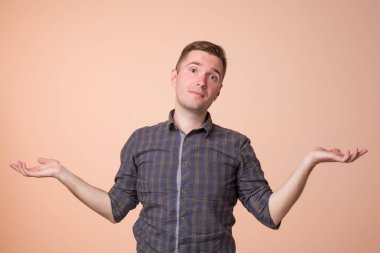Stüdyo hiçbir fikir hareketi var gösterilen karışık yakışıklı adam portresi. Omuzlarında shrugging ve renkli arka plan üzerinde ayakta eller yükselterek Avrupa adam.
