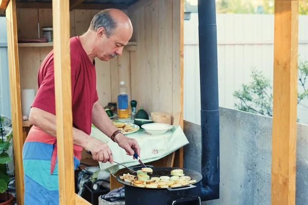 Man cooking a zucchini in the backyard.