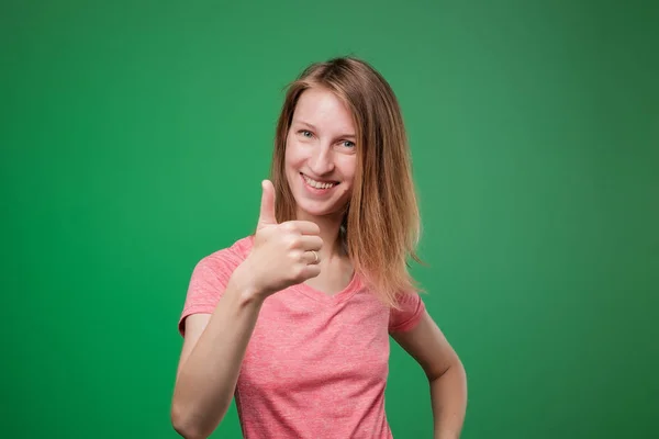 Jovem feliz dando polegares no fundo verde — Fotografia de Stock