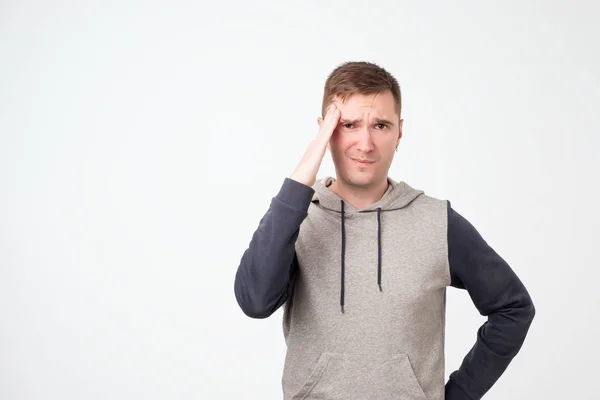 Bouleversé malheureux européen homme étudiant serrant la tête avec les mains, se tordant dans la douleur, souffrant de maux de tête . — Photo