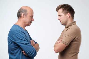 Mature father and son looking on each other face to face. They quarreled. To make claims and reproaches clipart