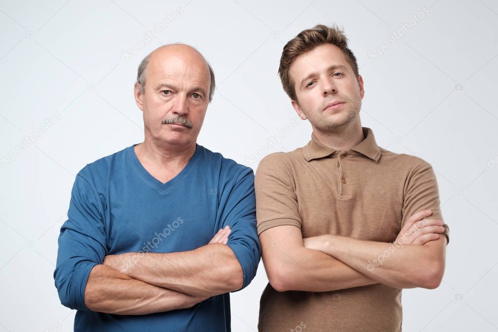 Portrait of mature father and son standing with serious expression on face. Good relatios in family. Together we are force concept