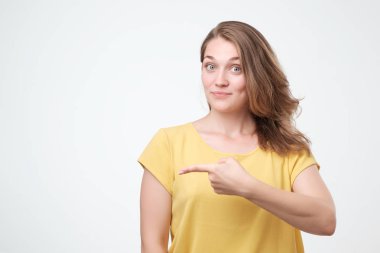 Genç güzel kadın nesnenin sol işaret ediyor. Kız gülümsüyor ve yan işaret. Metniniz için yer.