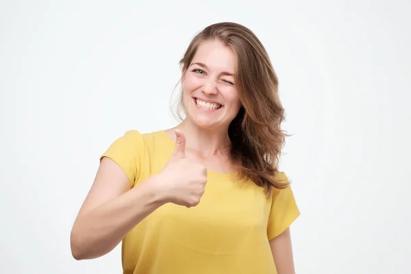 Щаслива молода жінка дає великі пальці на білому тлі — стокове фото