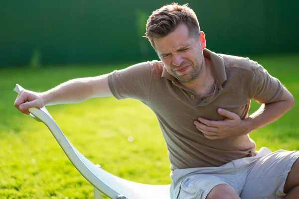 Jonge caucasain man hartaanval zittend buiten — Stockfoto