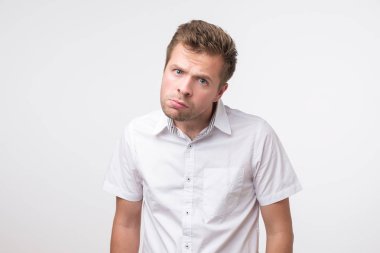Genç adam memnun frowns ve hadisler görünüyor. Olumsuz olayların alındaki kırışıklıklar