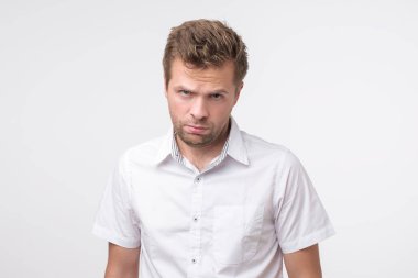 Genç adam memnun frowns ve hadisler görünüyor. Olumsuz olayların alındaki kırışıklıklar