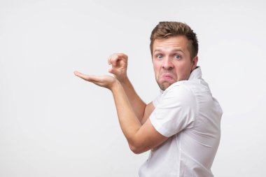 Pozitif yakışıklı adam gösterir bir şey çok küçük veya küçük, şüpheli durumda olmak, whitebackground karşı poz veriyor.