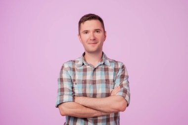 Kendine güvenen genç yakışıklı adam geçti ve pembe bir arka plan karşı dururken gülümseyen silah tutmak