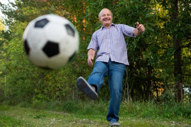 Olgun beyaz adam açık bir futbol topu tekmeleme. Topu bulanık.