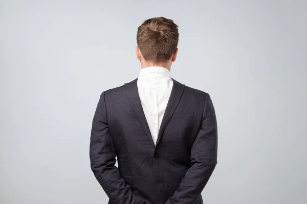 Studio shot of a mature caucasian man wearing his suit on backwards, gray background — Stock Photo, Image