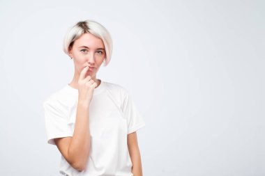 ciddi kadın modeli kısa renkli saç modeli ile parmaklarını ağız yakın tutar, önemli bilgileri hatırlamak çalışır