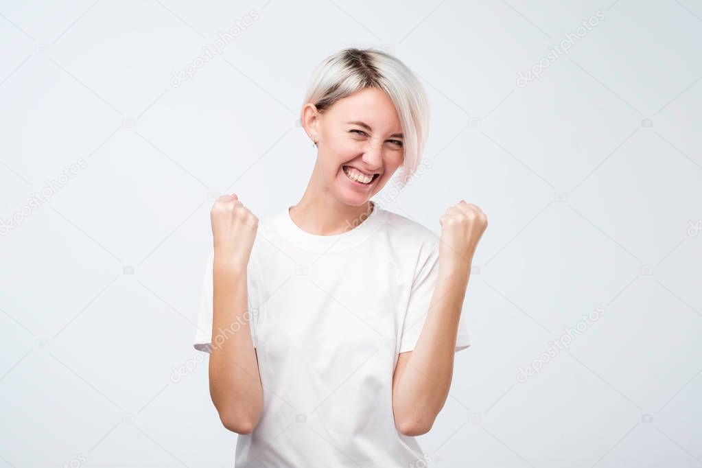 Excited cheerful teenager girl model with joyful expression, cheers and clenches fists, celebrates her success