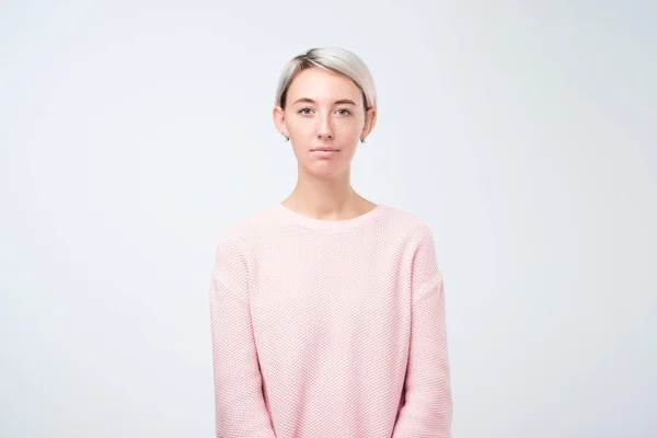 Портрет стильной молодой красивой женщины, улыбающейся стоя в розовом свитере на белом фоне студии — стоковое фото