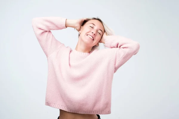 Junge schöne kaukasische Dame in rosa Pullover Stretching nach dem Aufwachen — Stockfoto