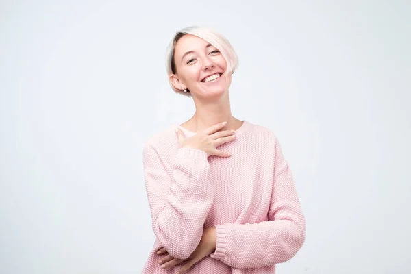 Mulher caucasiana agradável com cabelo curto tingido vestindo suéter rosa sorrindo amplamente e mantendo a mão na bochecha — Fotografia de Stock