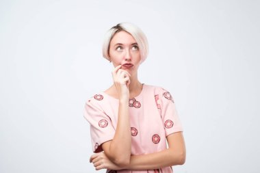 Pembe elbiseli sevimli genç kadın hakkında bir şeyler düşünüyor.