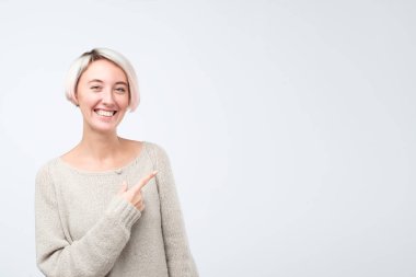 Gülümseyen boyalı kısa saç işaret parmağı uzakta genç kadın