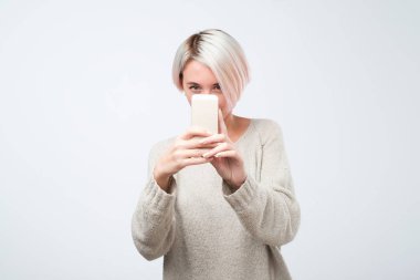 Kısa boyalı saçlı Genç Avrupa kadın Smartphone'da fotoğraf alma