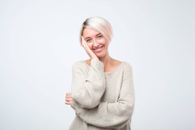 Gri arka plan üzerinde duran gülümseyen genç kafkas kadın