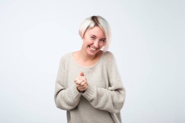 Gri arka plan üzerinde duran gülümseyen genç kafkas kadın