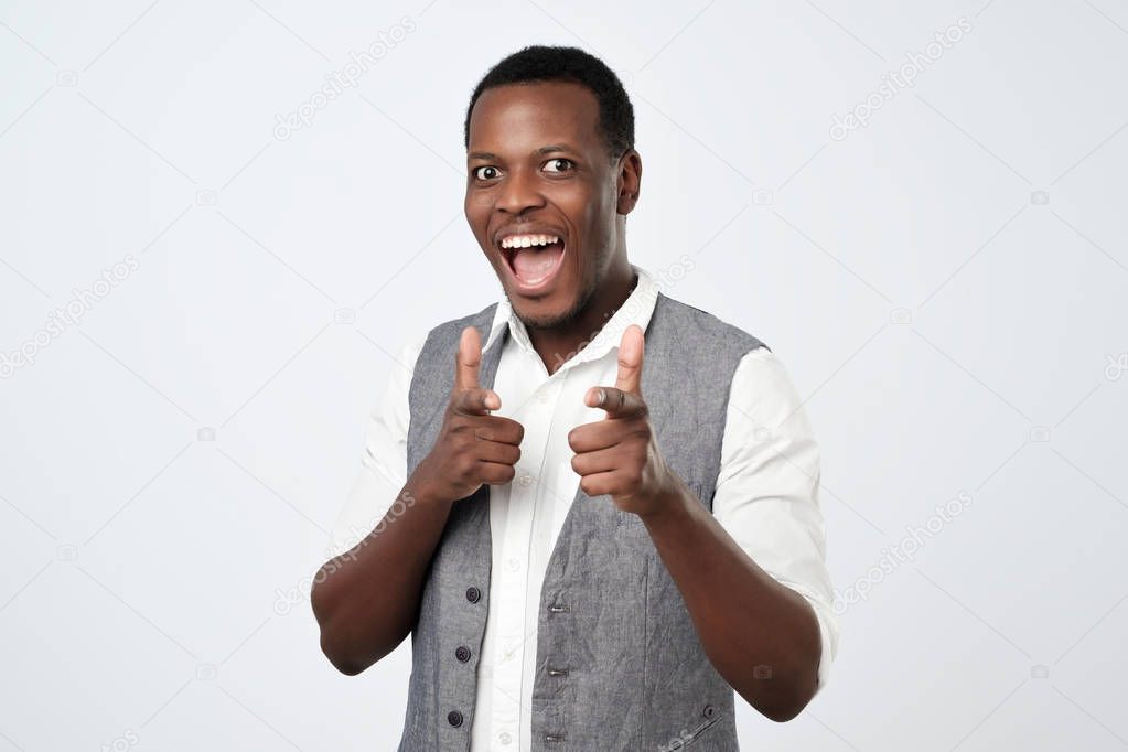 Young handsome african man with two hands guns sign gesture pointing at you camera
