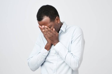 Yüzünü elleriyle ağlayarak süre kapsayan üzgün ifade ile yetişkin Afrika adam.