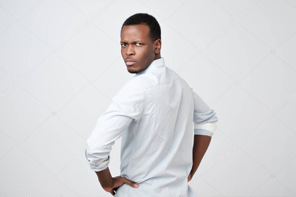 Man in white shirt looking behind at camera over his shoulder showing critical attitude.