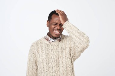 Pişmanlık yanlış yapıyor. Afrika genç adam, başındaki gri arka plan üzerinde el tokat.