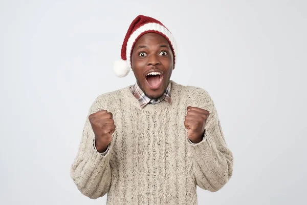 Funny christmas african man in red hat over grey background — Stock Photo, Image