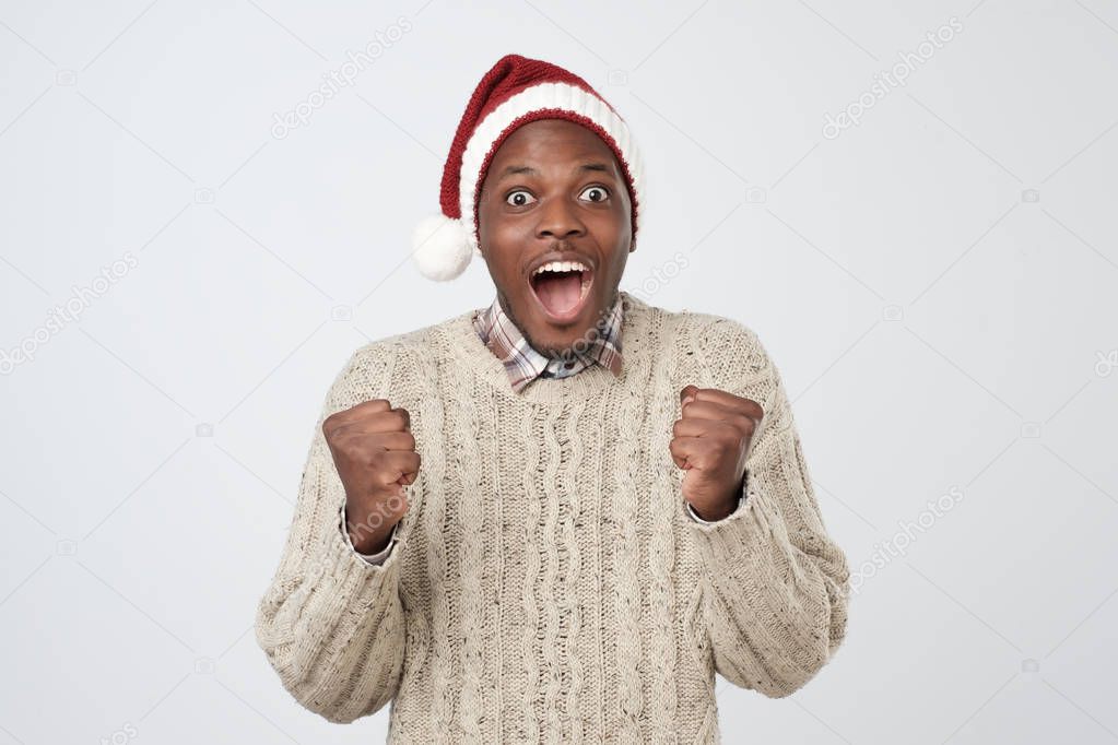 Funny christmas african man in red hat over grey background